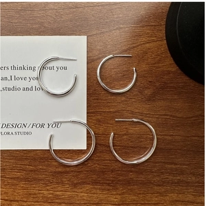 Macro detail of S925 sterling silver hoop earrings in two sizes on minimalist background