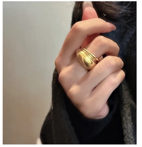 Detailed macro view of a polished gold dome ring worn on a finger with minimalist style