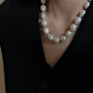 Collana di perle barocche con cordino nero indossata su una maglia nera con scollo a V