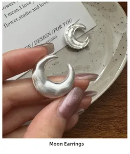 Detail of matte S925 sterling silver moon earrings with brushed metal finish