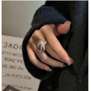 Polished silver oval ring on model's hand with black tweed coat minimalist fashion style