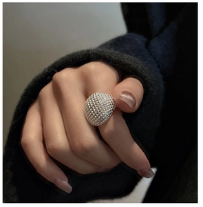 Macro shot of silver textured ring featuring dense bead texture on a model hand