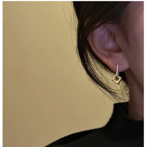 Detail view of two-tone S925 silver ear buckle with a gold hollow square charm on model