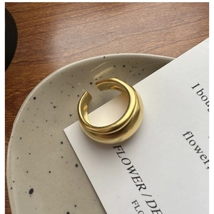 Close-up of minimalist gold matte wide-band open ring on a decorative ceramic plate