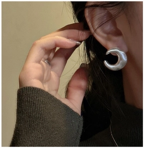 Detail of chunky silver hoop earring with polished finish on model's ear