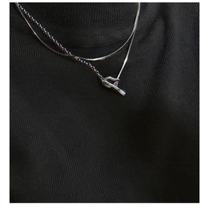 Detail of double-layered silver necklace with twisted knot on black turtleneck sweater