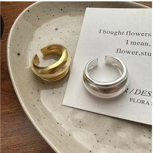 Close-up of matte gold and silver dome rings on a textured ceramic plate