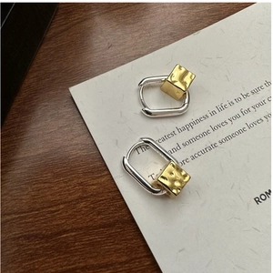 Detail of S925 silver square earrings with gold hammered cube charms on a wooden surface