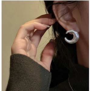 Close-up of minimalist S925 sterling silver crescent earrings with polished finish on model