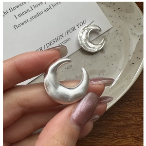 Close-up of S925 sterling silver crescent earrings showing the matte brushed texture