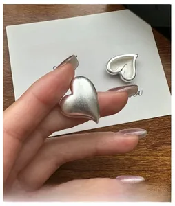 Macro shot of matte silver heart earrings showing brushed metal texture and fine details