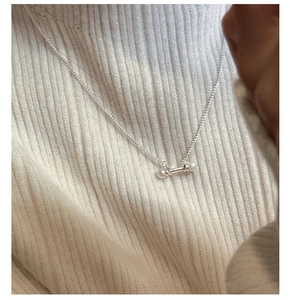 Detail showing an S925 silver balance bar necklace with white pearls on a model