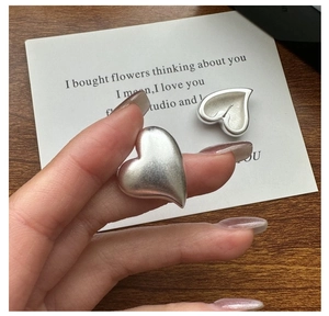 Detailed view of matte S925 sterling silver heart earrings with brushed metal texture