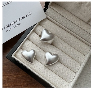 Macro detail of matte S925 sterling silver heart ring and studs in a jewelry box