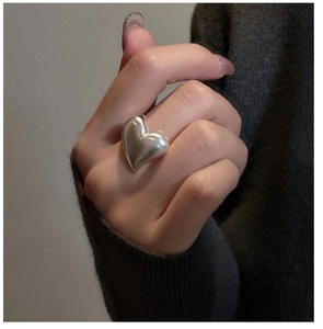 Close-up of polished S925 sterling silver heart ring worn on finger in a stylish minimalist look