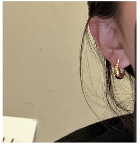 Gros plan d'une boucle d'oreille goutte en or minimaliste avec une finition polie