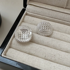 Macro shot of S925 sterling silver beaded dome stud earrings on textured beige linen