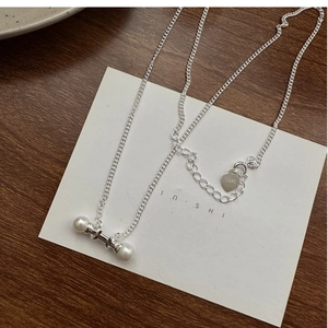 Detail of S925 silver necklace with pearl bar pendant and heart logo charm on a card