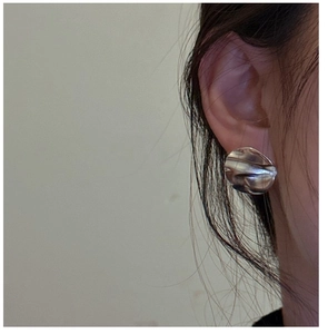 Detail of 925 sterling silver wrinkled stud earrings worn to show texture and scale