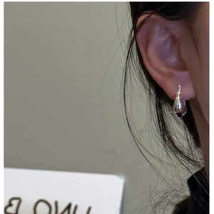 Gros plan d'une boucle d'oreille goutte en argent S925 portée par un mannequin