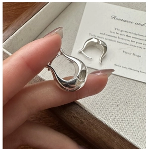 Vue rapprochée de boucles d'oreilles minimalistes en argent S925 poli miroir avec design unique