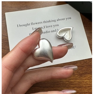 Close-up of S925 sterling silver matte heart stud earrings with a refined brushed texture