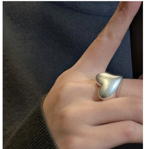 Detailed view of a bulky S925 sterling silver heart ring worn on the finger