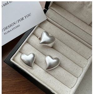 Macro detail of matte S925 sterling silver heart ring and earrings set in jewelry box