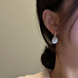 Close-up of S925 sterling silver drop earrings with white shell on model's ear