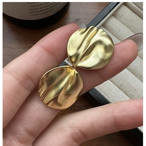 Detail shot of 925 silver golden earrings with textured wavy pleated finish and matte surface