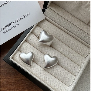 Detailed view of matte silver puffed heart ring and earrings set in a velvet box
