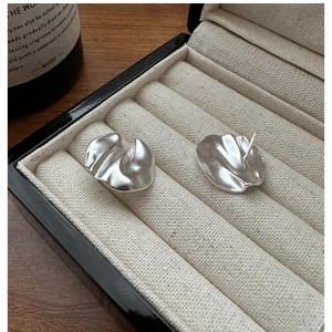 Macro shot of matte 925 silver stud earrings with wavy texture in a jewelry box