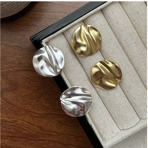 Detailed view of gold and silver textured round stud earrings on a ribbed jewelry tray