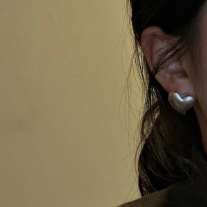 Minimalist S925 sterling silver heart stud earrings worn by model on beige background