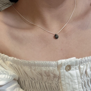 Gros plan du collier en argent sterling S925 avec un pendentif rond en pierre sombre