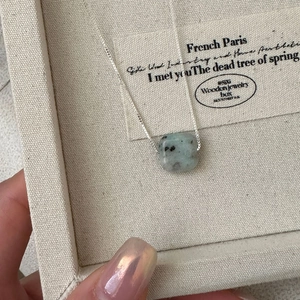 Gros plan du collier en argent S925 avec pendentif carré en pierre sur lin
