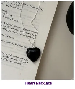 Detail shot of a black onyx heart necklace on vintage book pages with beaded silver chain