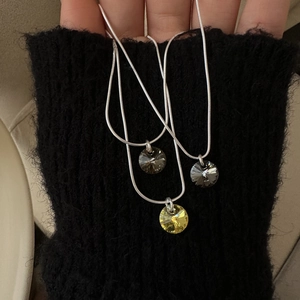 Détail de colliers en argent S925 avec pendentifs en cristal gris et jaune facetté