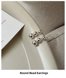 Macro shot of silver bead earrings with four graduated spheres on a minimalist tray