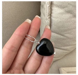 Detailed close-up of a smooth black onyx heart pendant on a S925 silver bead chain