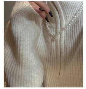 Détail du collier à pendentif cœur en argent S925 avec perles naturelles sur pull blanc