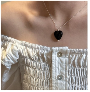Close-up of S925 silver beaded chain with a black onyx heart pendant on a model