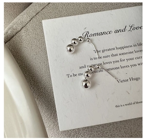 Macro detail of 925 sterling silver gradient bead earrings on a textured paper background