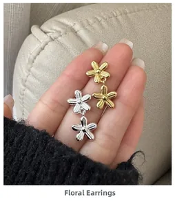 Dettaglio di orecchini a fiori sovrapposti argento e oro con texture a strisce