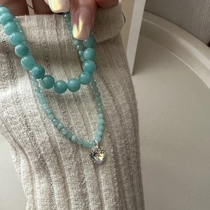 Detail of S925 silver mint green beaded necklace with faceted crystal pendant on sweater