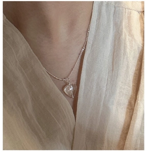 Dettaglio del ciondolo a cuore in cristallo su collana di perline d'argento al collo