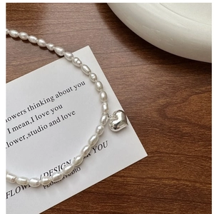 Détail du pendentif cœur en argent S925 et perles naturelles sur un bureau en bois