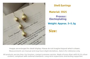 Détail macro de boucles d'oreilles coquillage dorées asymétriques en argent S925