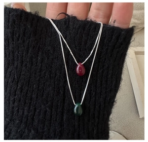 Detail of teardrop pendant necklace in wine red and dark green on a silver chain