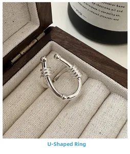 Macro detail of silver U-shaped ring with textured threading in a wooden jewelry box